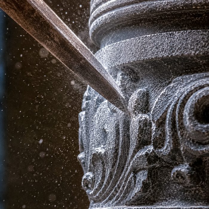Chisel cutting detail into carved stone