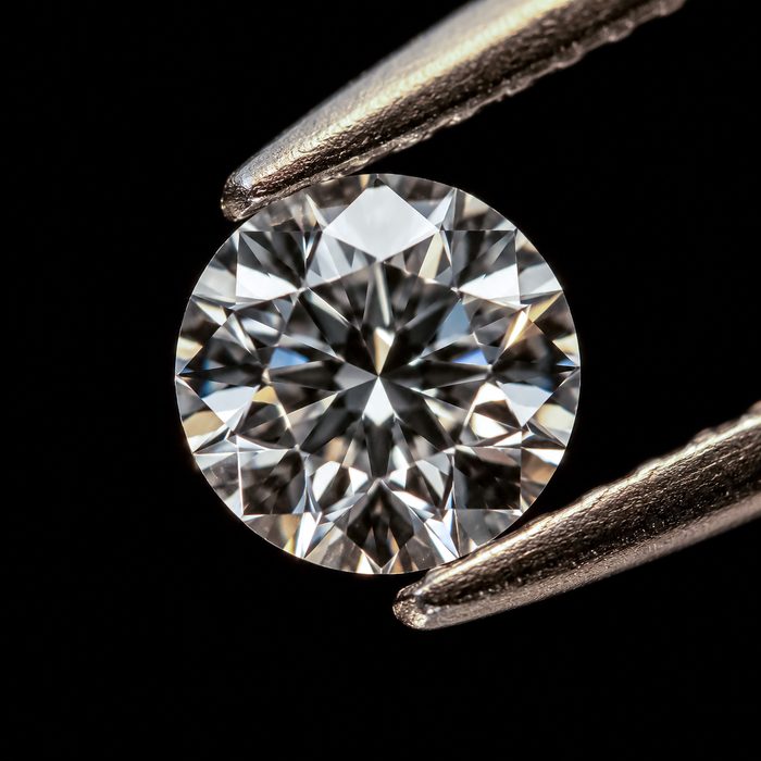 A cut diamond held with tweezers